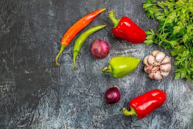 Vista superior de verduras frescas con pimientos y ajo en la mesa gris claro