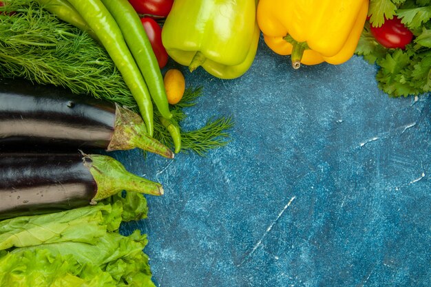 Vista superior de verduras frescas pimientos berenjenas lechuga sobre fondo azul.