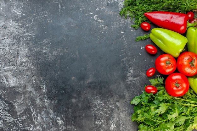 Vista superior de verduras frescas pimientos rojos y verdes tomates cherry eneldo tomates perejil sobre superficie oscura con lugar de copia