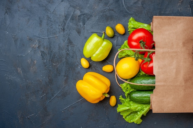 Vista superior de verduras frescas pimientos tomates pepinos lechuga cumcuats en bolsa de compras sobre fondo oscuro espacio libre