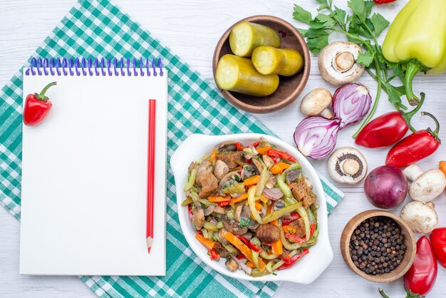 Vista superior de verduras frescas con plato de carne en rodajas y bloc de notas en el escritorio de luz, comida vegetal carne