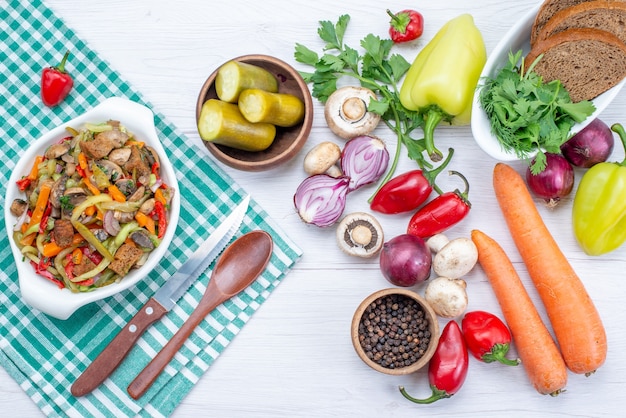 Vista superior de verduras frescas con plato de carne en rodajas y hogazas de pan en carne ligera, comida vegetal