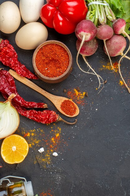 Vista superior de verduras frescas en polvo de pimiento rojo en huevos de cuchara de madera en el espacio libre de la mesa