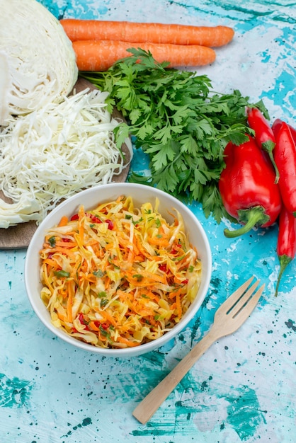 Vista superior de verduras frescas en rodajas Ensalada de piezas largas y delgadas dentro del plato con verduras, repollo, pimientos en el escritorio azul brillante, comida, ensalada de verduras