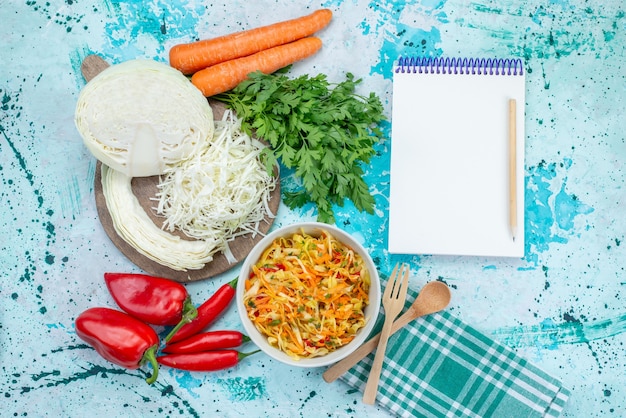 Vista superior de verduras frescas en rodajas Ensalada de piezas largas y delgadas dentro del plato con verduras, repollo, pimientos en el escritorio azul brillante, comida, ensalada de verduras
