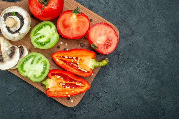 Vista superior de verduras frescas setas tomates rojos y verdes pimientos en una tabla de cortar