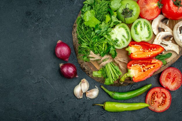 Vista superior de verduras frescas setas tomates rojos y verdes pimientos verdes en tablero rústico