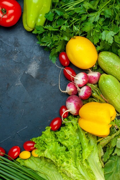 Vista superior de verduras frescas tomate calabacín rábano limón perejil tomates cherry lechuga sobre superficie oscura con espacio libre