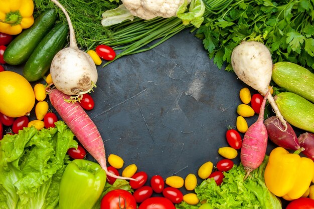 Vista superior de verduras frescas tomates cherry lechuga cumcuat eneldo pimiento amarillo pepino calabacín espacio libre en el centro