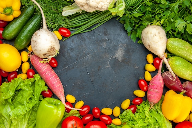 Vista superior de verduras frescas tomates cherry lechuga cumcuat eneldo pimiento amarillo pepino calabacín espacio libre en el centro