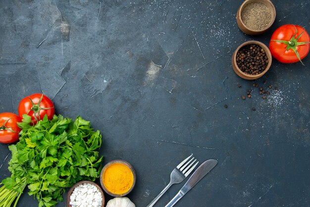 Vista superior de verduras frescas con tomates y condimentos en la mesa oscura