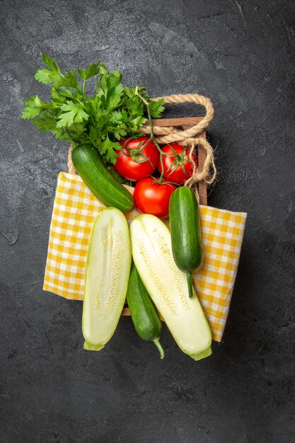 Vista superior de verduras frescas tomates pepinos calabazas y verduras en superficie gris