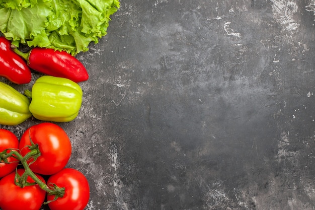 Foto gratuita vista superior de verduras frescas tomates pimientos lechuga en lugar libre de superficie oscura