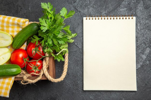 Vista superior de verduras frescas tomates rojos pepinos y calabazas con verduras en la superficie gris