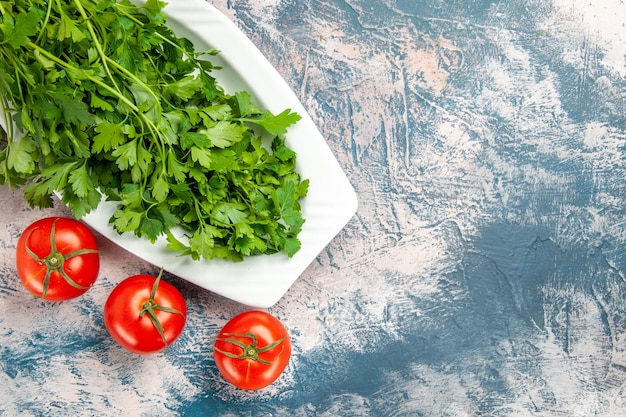 Vista superior de verduras frescas con tomates sobre fondo azul claro