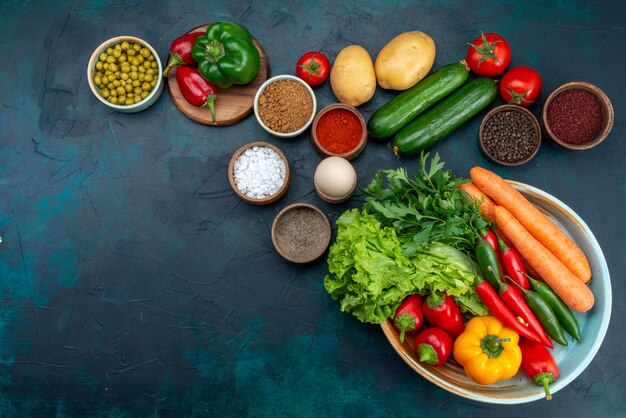 Vista superior de verduras frescas con verduras y condimentos en el escritorio azul oscuro, almuerzo, ensalada, comida vegetal