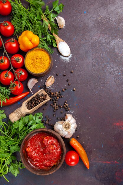 Vista superior de verduras frescas con verduras y condimentos en el escritorio oscuro