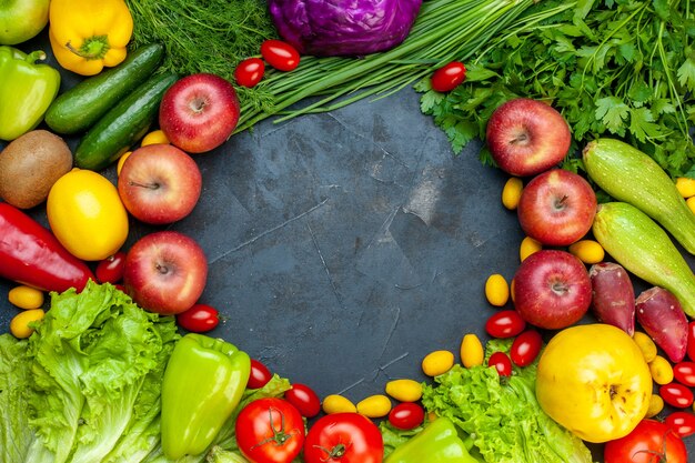 Vista superior verduras y frutas lechuga tomates pepino eneldo tomates cherry calabacín cebolla verde perejil manzana limón kiwi espacio libre en el centro