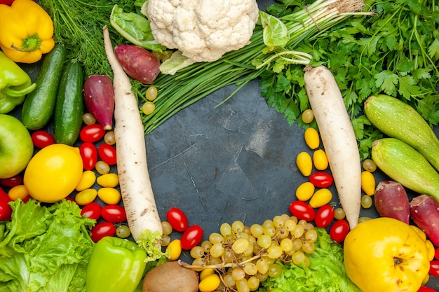 Foto gratuita vista superior de verduras y frutas, tomates cherry, lechuga cumcuat, membrillo, uva, limón, coliflor, rábano blanco, perejil, calabacín, pepinos, espacio libre en el centro