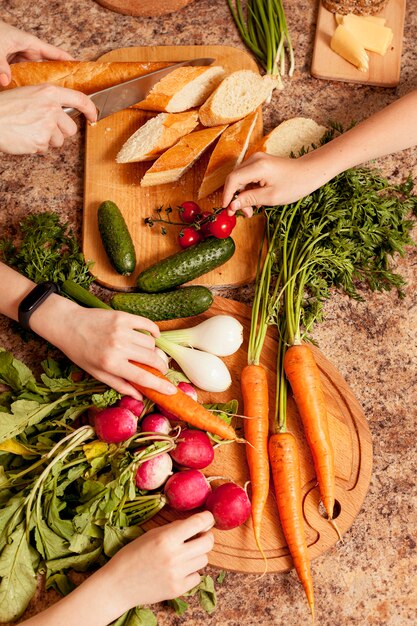 Vista superior de verduras en la mesa con personas preparándolas