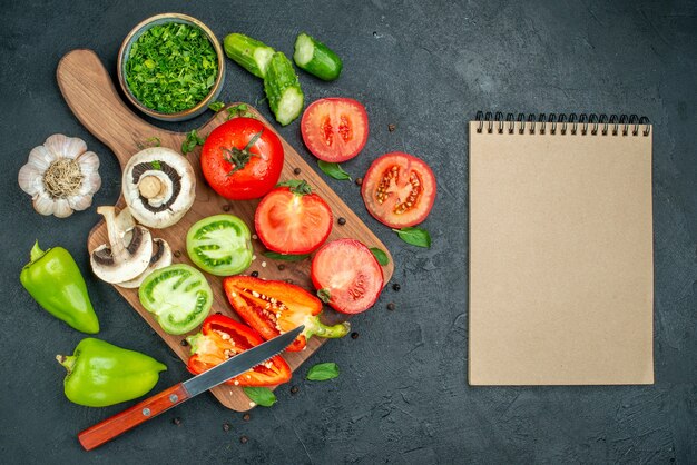 Vista superior de verduras pepinos tomates verdes y rojos pimientos cuchillo en la tabla de cortar