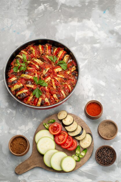 Vista superior de verduras en rodajas como tomates y berenjenas frescas y cocidas en la mesa de luz comida de verduras frescas