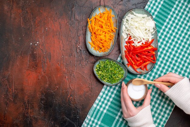 Vista superior de verduras en rodajas, zanahoria, repollo y pimiento con verduras en la mesa oscura