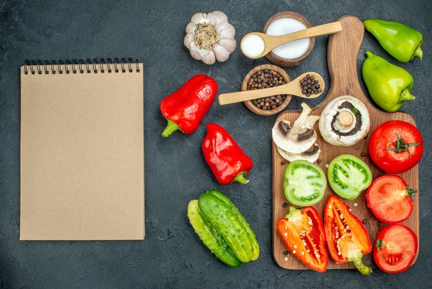 Vista superior de verduras setas tomates rojos y verdes pimientos rojos en la tabla de cortar