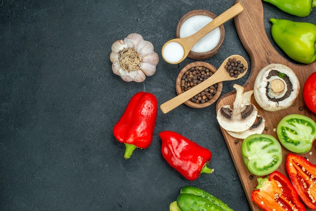 Vista superior de verduras setas tomates rojos y verdes pimientos rojos en la tabla de cortar