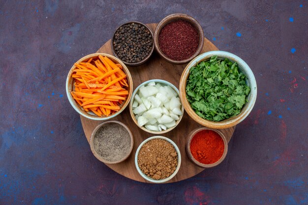 Vista superior de verduras y verduras con condimentos en la superficie oscura de alimentos vegetales pimienta