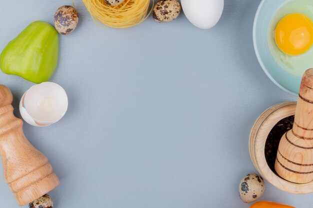 Vista superior de la yema de huevo de gallina fresca y blanca en un recipiente azul con cáscaras de huevo agrietadas con salero sobre un fondo blanco con espacio de copia