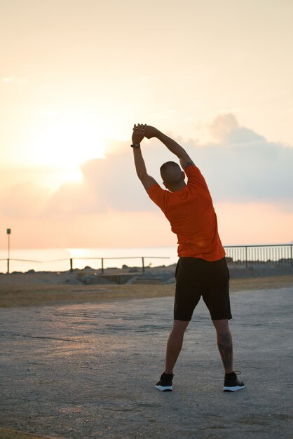 Vista trasera del atleta masculino haciendo ejercicios de flexión lateral