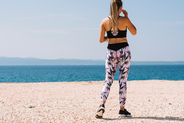 Foto gratuita vista trasera, de, un, condición física, mujer joven, posición, en, playa