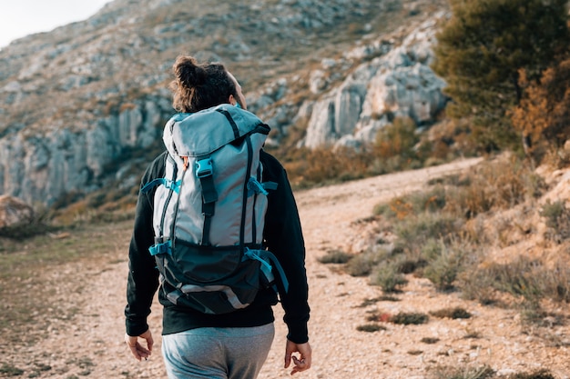 Vista trasera de un excursionista masculino con mochila de senderismo en las montañas