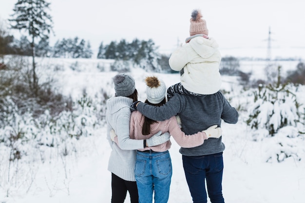 Vista trasera de la familia admirando el paisaje de invierno