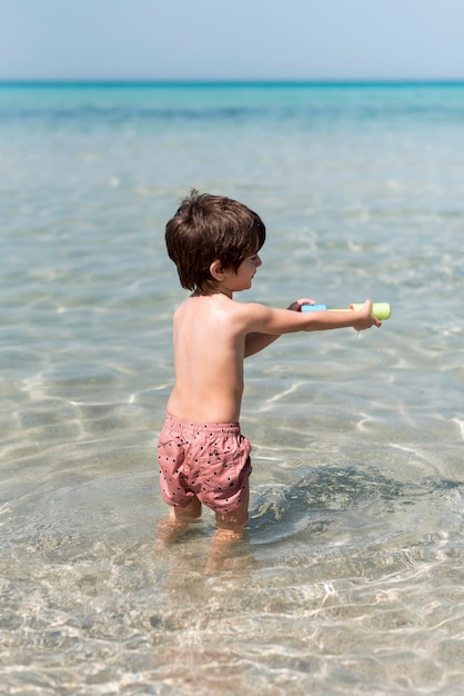 Vista trasera foto de un niño jugando con pistola de agua