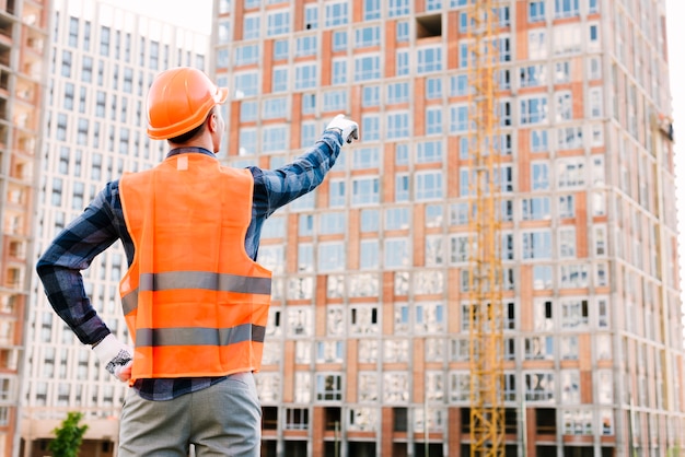 Foto gratuita vista trasera del hombre apuntando al edificio