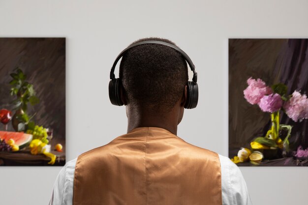 Vista trasera del hombre con auriculares en la galería de arte.