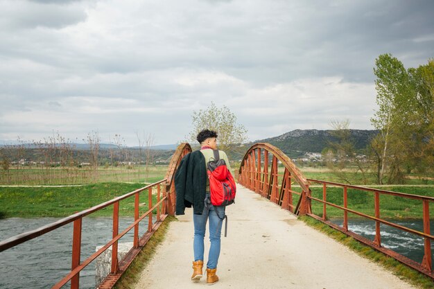 Vista trasera del hombre caminando en el puente sobre el río