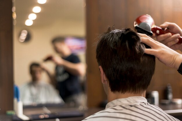 Vista trasera hombre cortándose el pelo