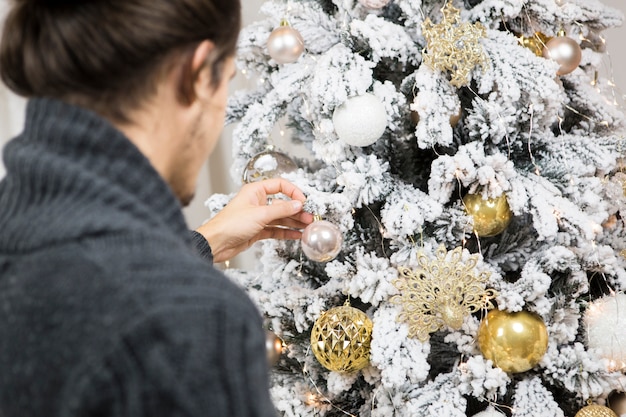 Vista trasera de hombre decorando árbol de navidad