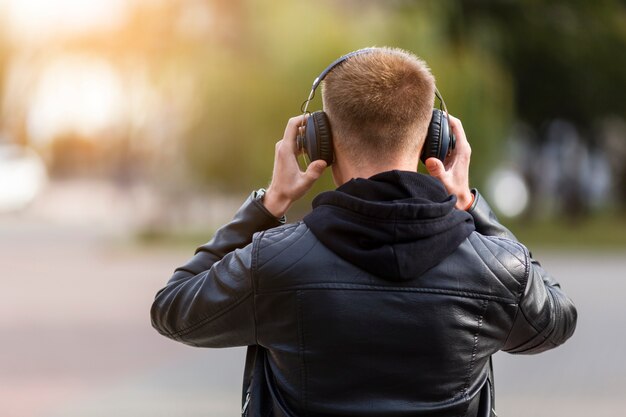 Vista trasera hombre escuchando música en auriculares