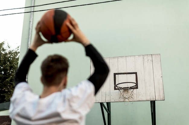 Foto gratuita vista trasera hombre lanzando una pelota de baloncesto