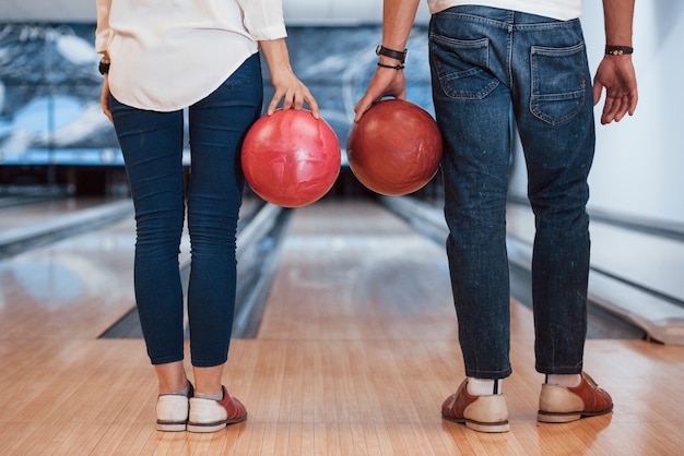 Vista trasera del hombre y la niña de pie con bolas de bol en las manos en el club