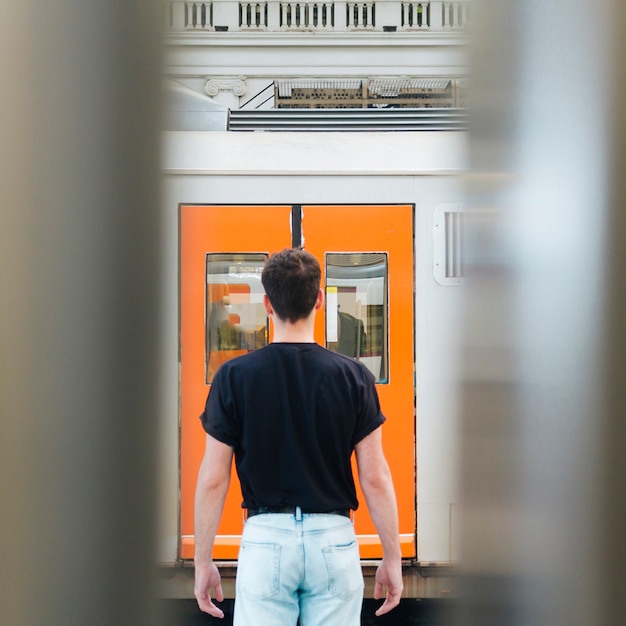 Foto gratuita vista trasera del hombre parado frente a la puerta del ferrocarril