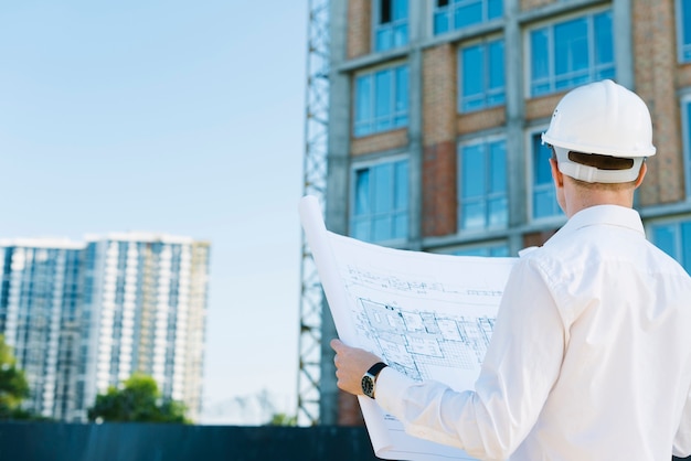 Vista trasera del hombre con planes de construcción