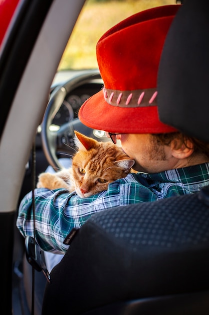 Foto gratuita vista trasera del hombre sentado en el asiento del conductor con un gato