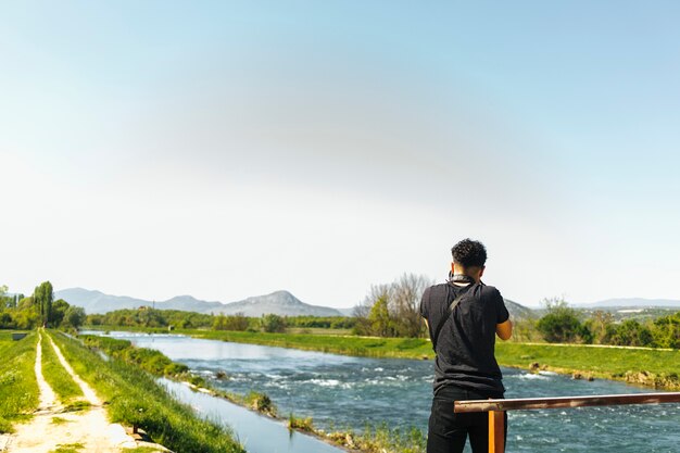 Vista trasera del hombre tomando una foto del río que fluye