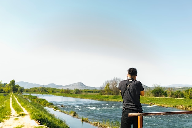 Vista trasera del hombre tomando una foto del río que fluye