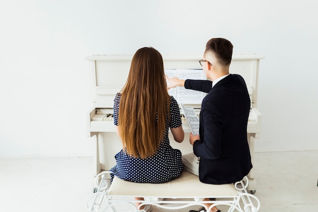 Foto gratuita vista trasera del joven enseñando a su novia piano